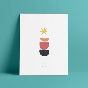 Puede incluir: Impresión de arte abstracto con una estrella amarilla, círculos naranja, rojo y negro apilados uno encima del otro. La impresión tiene el texto "Angie + Joy" en la parte inferior.