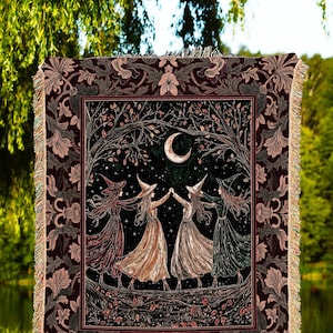 Peut inclure: Une couverture décorative en tapisserie avec une bordure sombre et ornée et une image centrale de sorcières dansant sous un croissant de lune. L'œuvre est encadrée par une bordure décorative et le texte "JOY OF PLANTS Original Fine Art Throws" est en bas.