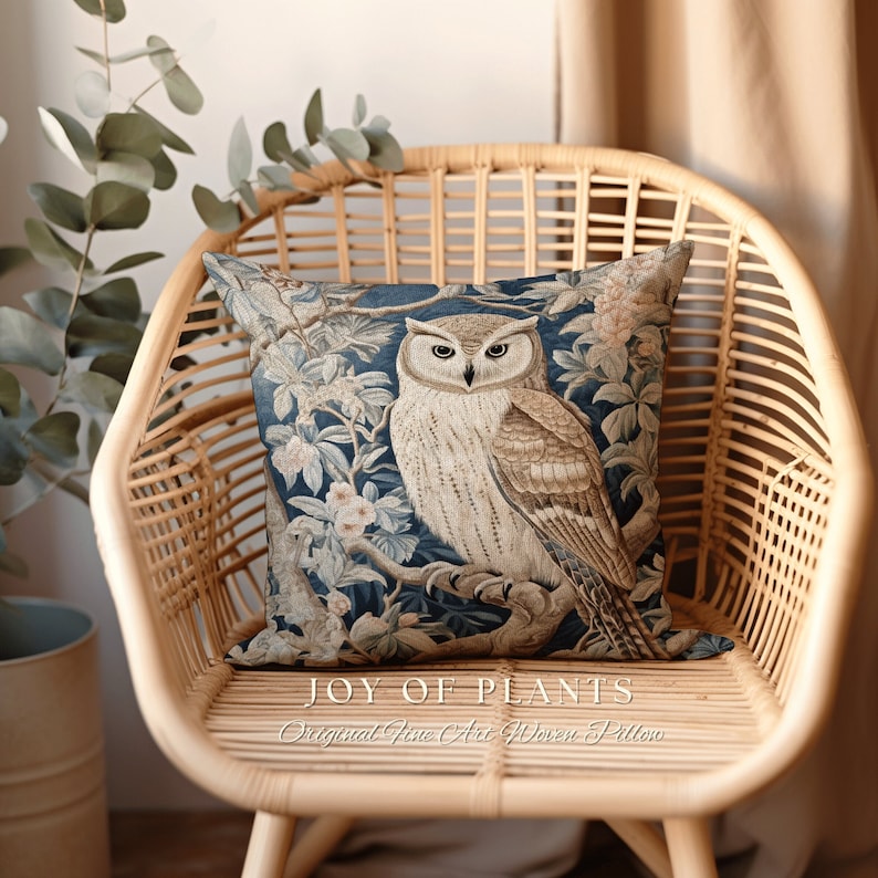 May include: A blue and brown woven throw pillow featuring a detailed illustration of an owl perched on a branch with flowers. The pillow has the text "JOY OF PLANTS Original Fine Art Woven Pillow" printed on the bottom.