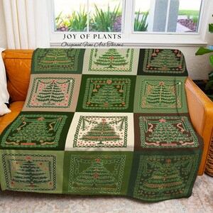 May include: A green and beige throw blanket with a patchwork design featuring Christmas trees. The blanket is draped over a brown leather couch with a white pillow. The text "JOY OF PLANTS Original Fine Art Throws" is visible.