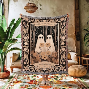 May include: A woven throw blanket with a romantic design. The blanket features two ghost figures holding sunflowers, with the text "TIL DEATH DO US PART" and the names "DYLAN & GABBY 2024". The blanket has a black background with floral and leaf accents.
