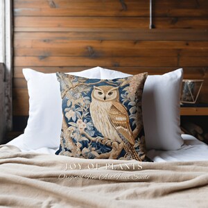 May include: A blue and brown throw pillow with a tapestry-style design featuring an owl perched on a branch with flowers. The pillow has the text "JOY OF PLANTS Original Fine Art Faux Suede" printed on the bottom.