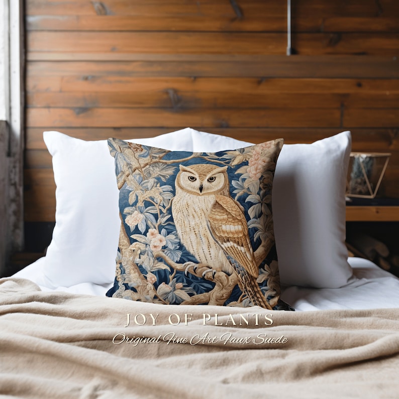 May include: A blue and brown throw pillow with a tapestry-style design featuring an owl perched on a branch with flowers. The pillow has the text "JOY OF PLANTS Original Fine Art Faux Suede" printed on the bottom.