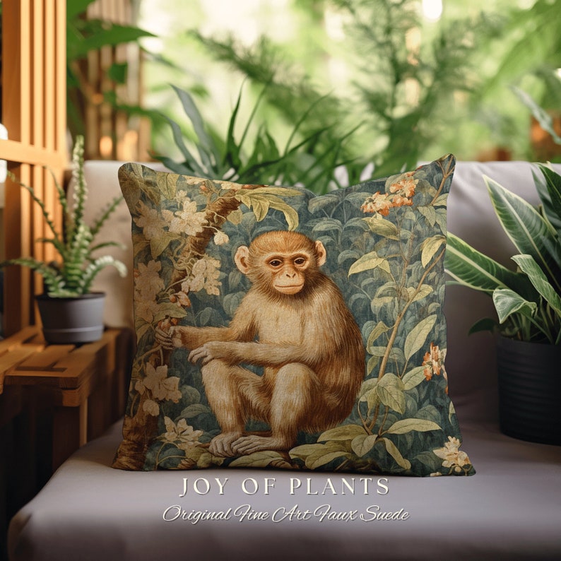 Pode incluir: Uma almofada decorativa com acabamento em camur&ccedil;a sint&eacute;tica apresenta uma ilustra&ccedil;&atilde;o vintage de um macaco sentado em um ambiente exuberante de selva. A almofada tem o texto "JOY OF PLANTS" e "Original Fine Art Faux Suede" impresso nela.