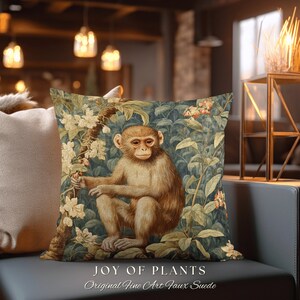 Pode incluir: Uma almofada decorativa com uma ilustra&ccedil;&atilde;o vintage de um macaco sentado em um ambiente exuberante de selva verde. A almofada &eacute; feita de tecido de camur&ccedil;a sint&eacute;tica e tem o texto "JOY OF PLANTS Original Fine Art Faux Suede".