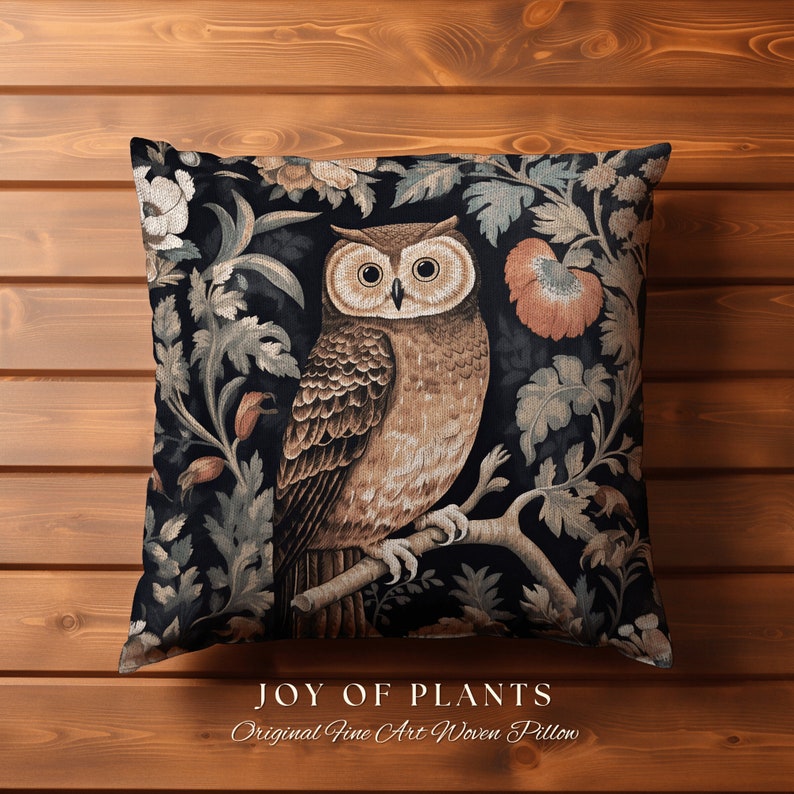Op de afbeelding: Een decoratief kussen met een zwarte achtergrond waarop een bruine uil op een tak zit, omringd door ingewikkelde bloemmotieven. Het kussen heeft de tekst "JOY OF PLANTS" en "Original Fine Art Woven Pillow" onderaan gedrukt.