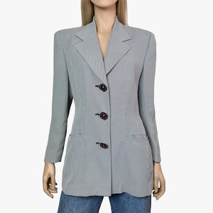 May include: A gray and white houndstooth blazer with three dark buttons. The blazer has a notched collar and two front pockets. The sleeves are long and the garment is displayed on a mannequin.