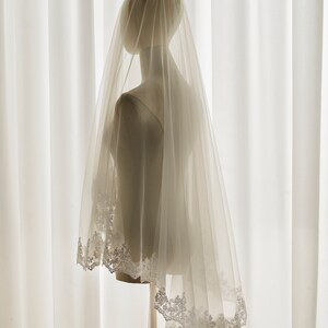 May include: A white bridal veil with a delicate lace trim. The veil is made of soft tulle and is perfect for a wedding ceremony.