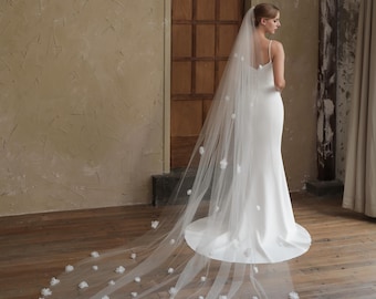 May include: A white bridal veil with a long train and delicate white flower embellishments.