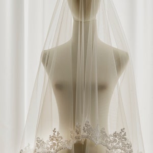 May include: A white bridal veil with a delicate lace trim. The veil is made of soft tulle and is perfect for a wedding ceremony.