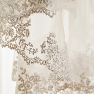 May include: White lace fabric with a delicate floral pattern. The lace is soft and flowing, with a subtle sheen.