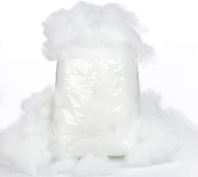 May include: A white plastic bag filled with white fluffy stuffing. The bag is surrounded by loose white stuffing.