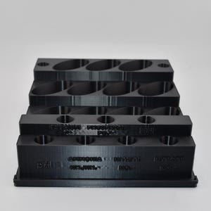 May include: A black plastic test kit organizer with multiple circular slots for vials. The front face features embossed text labels including pH, Ammonia NH3/NH4, Nitrite NO2, and Nitrate NO3. The middle section is labeled Calcium, Phosphate PO4, and KH.