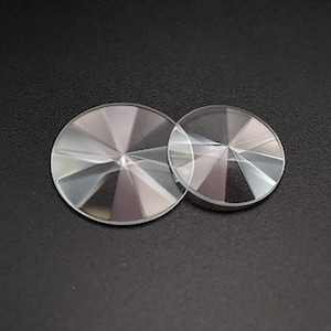 Puede incluir: Dos prismas redondos de cristal de vidrio transparente con un diseño facetado. El prisma más grande es ligeramente más grande que el más pequeño.