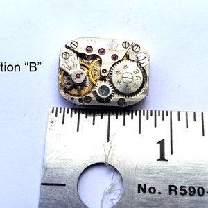 Peut inclure: Un mouvement de montre argent&eacute; avec des engrenages dor&eacute;s, mesurant environ 2,5 cm de diam&egrave;tre. Le mouvement porte une &eacute;tiquette blanche avec le texte "3AD" et "0081".