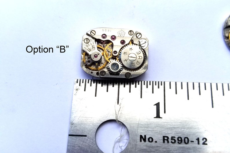 Peut inclure: Un mouvement de montre argent&eacute; avec des engrenages dor&eacute;s, mesurant environ 2,5 cm de diam&egrave;tre. Le mouvement porte une &eacute;tiquette blanche avec le texte "3AD" et "0081".