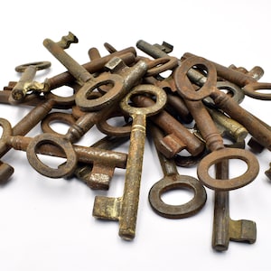 Puede incluir: Un montón de llaves antiguas, todas oxidadas y desgastadas, con una variedad de formas y tamaños. Las llaves están dispuestas en un patrón aleatorio, con algunas superpuestas.