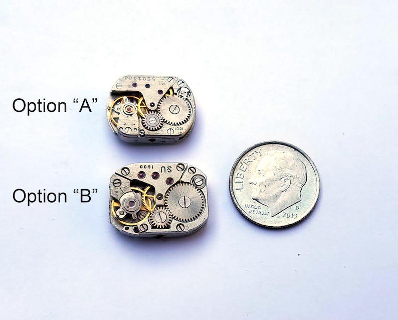 Peut inclure: Deux petits mouvements de montre argent&eacute;s, &eacute;tiquet&eacute;s "Option A" et "Option B", sont pr&eacute;sent&eacute;s &agrave; c&ocirc;t&eacute; d'une pi&egrave;ce de dix cents am&eacute;ricaine pour l'&eacute;chelle. Les mouvements sont complexes et d&eacute;taill&eacute;s, avec des engrenages et des ressorts visibles.