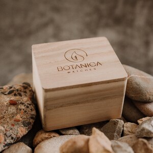 A Wooden Jewellery Box closed sitting on a bed of stones