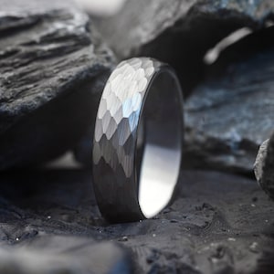 Silver ring with a textured band on a dark, textured surface