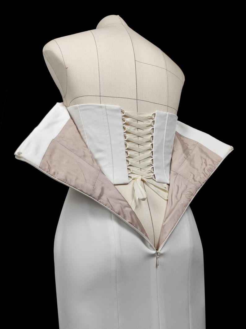 May include: A white corset with a white lace-up back. The corset is open in the front, revealing a white lining.