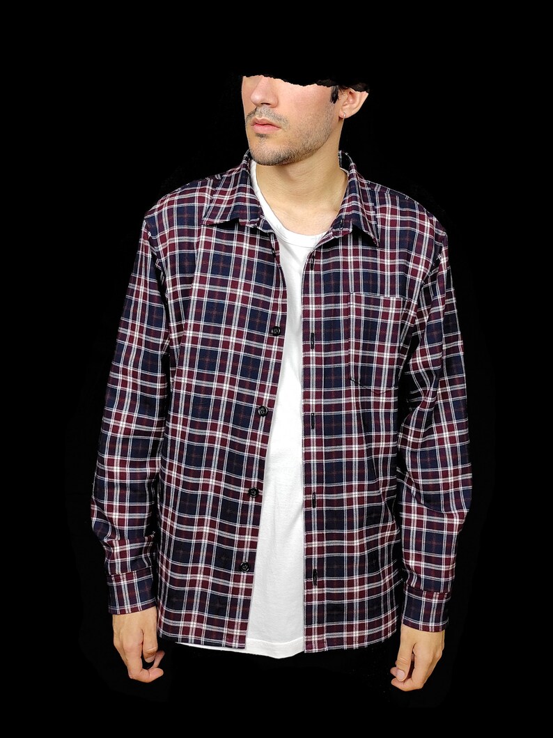 May include: A long-sleeved plaid shirt in shades of red, white, and blue. The shirt has a button-down collar and a relaxed fit.