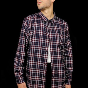 May include: A long-sleeved plaid shirt with a button-down collar. The shirt is a mix of red, blue, and white plaid.