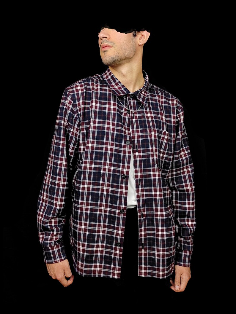 May include: A long-sleeved plaid shirt with a button-down collar. The shirt is a mix of red, blue, and white plaid.