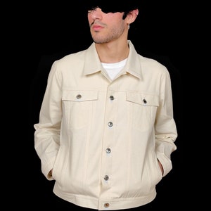 May include: A cream colored denim jacket with a button front closure and two chest pockets.