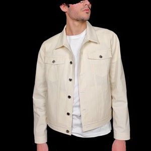 May include: A cream-colored denim jacket with a button-up front and two flap pockets. The jacket has a classic fit and is made of a soft, comfortable fabric.