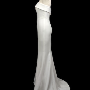 May include: A white off-the-shoulder, floor-length gown with a fitted bodice and a flowing skirt.