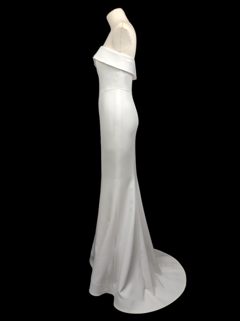 May include: A white off-the-shoulder, floor-length gown with a fitted bodice and a flowing skirt.