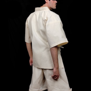Puede incluir: Un conjunto de camisa y pantal&oacute;n corto color crema con mangas cortas. La camisa tiene cuello mandar&iacute;n y corte holgado. El pantal&oacute;n corto llega a la rodilla con cintura con cord&oacute;n. El conjunto es de tejido ligero.