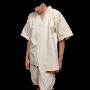 Puede incluir: Kimono color crema con pantalones cortos a juego. La parte superior tiene mangas anchas y un cierre envolvente con una corbata. Los pantalones cortos son holgados con lazos en los pu&ntilde;os. El conjunto est&aacute; hecho de tela ligera.