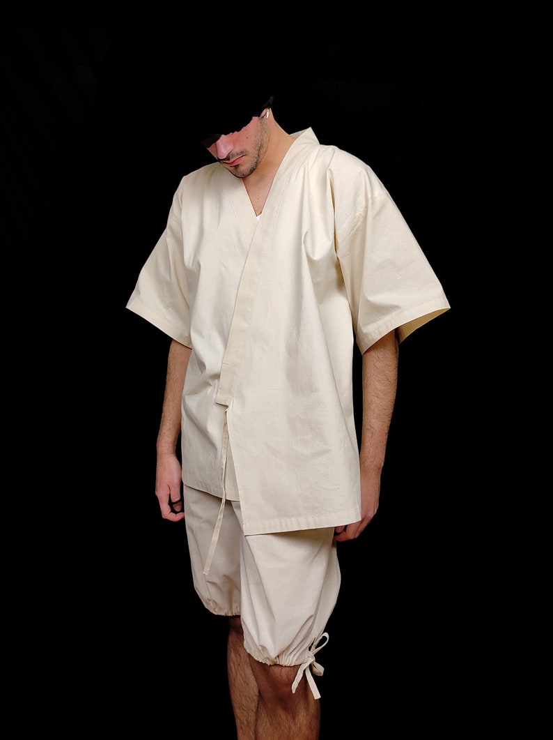 Puede incluir: Kimono color crema con pantalones cortos a juego. La parte superior tiene mangas anchas y un cierre envolvente con una corbata. Los pantalones cortos son holgados con lazos en los pu&ntilde;os. El conjunto est&aacute; hecho de tela ligera.