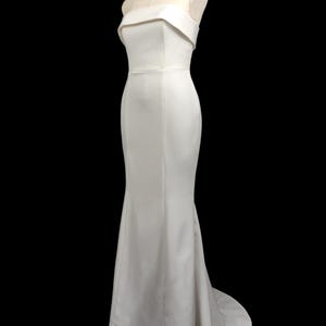 May include: A white strapless mermaid-style wedding dress with a fitted bodice and a flowing skirt.