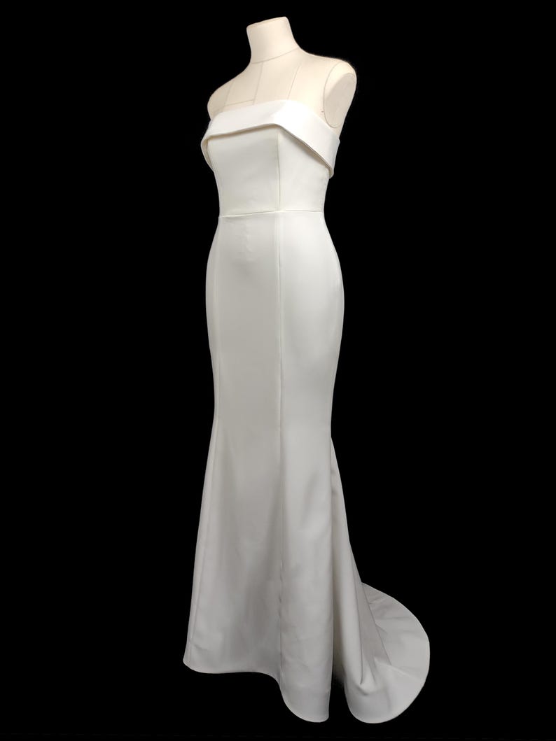 May include: A white strapless mermaid-style wedding dress with a fitted bodice and a flowing skirt.
