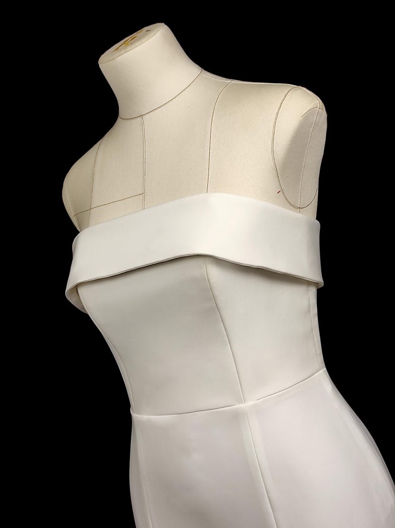 May include: A white strapless dress with a fitted bodice and a flowing skirt. The dress is made of a smooth, satin-like fabric.
