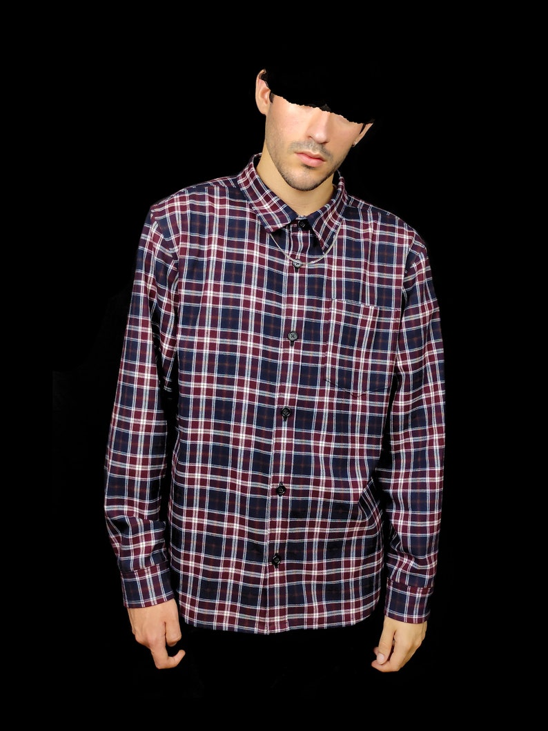 May include: A long-sleeved plaid shirt with a red, white and blue pattern. The shirt has a button-down collar and a chest pocket.