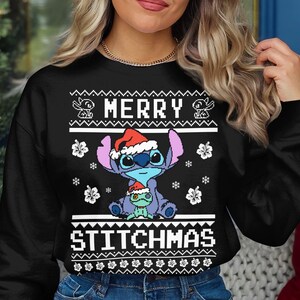 May include: Black Christmas sweater with a white snowflake pattern. The sweater features a blue Stitch character from Lilo & Stitch wearing a Santa hat and holding a small green alien. The text "Merry Stitchmas" is printed on the sweater.