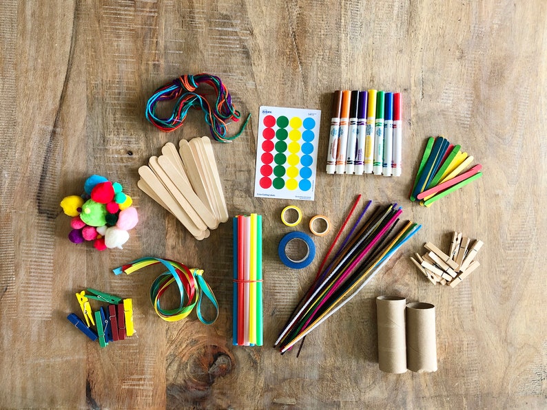 Op de afbeelding: Een verzameling kleurrijke knutselspullen, waaronder pompoenen, garen, houten stokjes, rietjes, pijpenragers, tape, stiften en papieren cirkels.