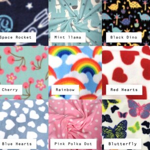 May include: A grid of nine fabric swatches featuring various patterns: Space Rocket, Mint Llama, Black Dino, Cherry, Rainbow, Red Hearts, Blue Hearts, Pink Polka Dot, and Blutterfly. Each swatch displays a distinct colorful print on fleece.