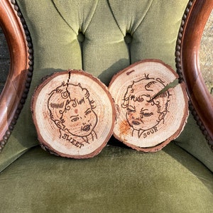 Può includere: Due fette di legno con volti intagliati. La fetta a sinistra dice "Sweet" e la fetta a destra dice "Sour".