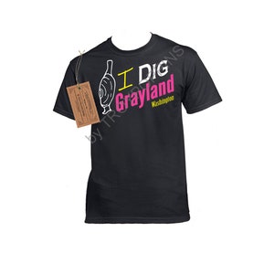 May include: Black t-shirt with a white graphic of a digging shovel and the text "I Dig Grayland Washington" in pink and yellow.