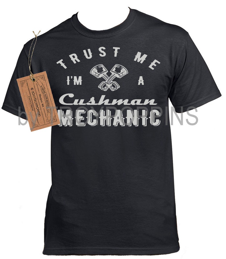 May include: A black t-shirt with a white graphic that says "Trust me I'm a Cushman Mechanic" with a pair of crossed pistons.