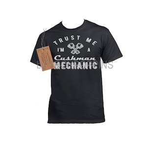 May include: Black t-shirt with white text that reads "Trust me I'm a Cushman Mechanic" with a graphic of two crossed wrenches.