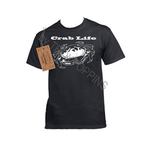 May include: Black t-shirt with a white crab illustration and the text "Crab Life" printed on the front.