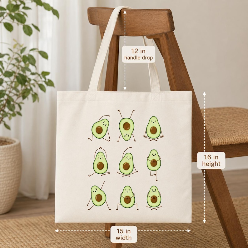 May include: A cream-colored tote bag with a whimsical design of avocados in yoga poses. The bag is 15 inches wide and 16 inches high, with a 12-inch handle drop. The avocados are green with brown pits, and the bag is made of a sturdy fabric.