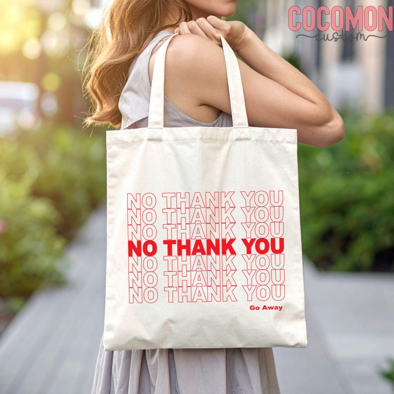 May include: Cream-colored tote bag with red text that reads "NO THANK YOU" repeated multiple times. The phrase "Go Away" is printed at the bottom. The bag has two handles.
