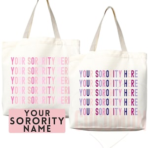 Op de afbeelding: Twee witte canvas tassen met roze en paarse tekst. De tekst op de ene tas is "YOUR SORORITY HERE" en wordt meerdere keren herhaald. De tekst op de andere tas is "YOUR SORORITY NAME".
